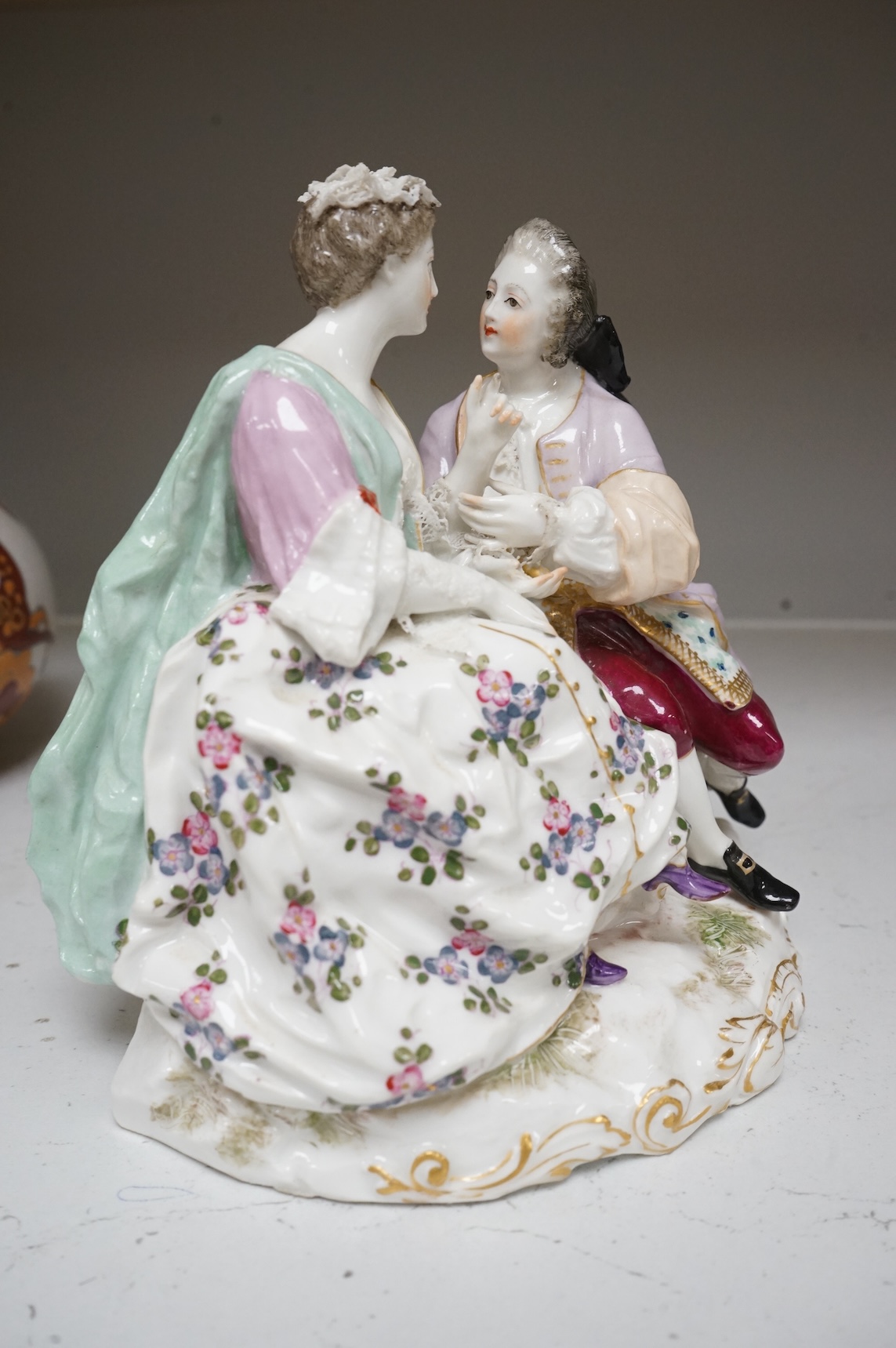 A German porcelain group of a seated courting couple, 16.5cm high